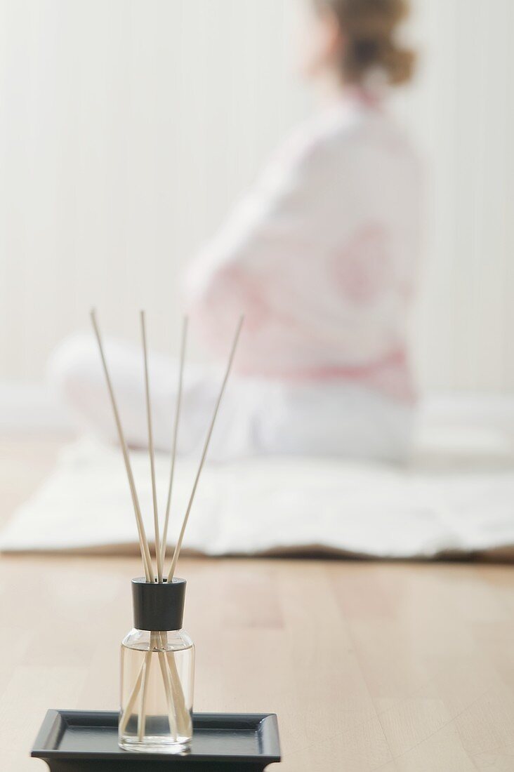 Incense sticks with scented oil, woman sitting cross-legged