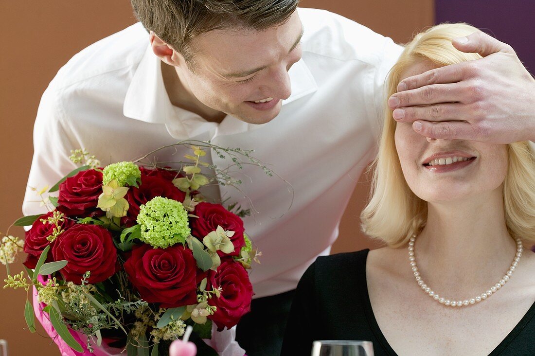 Mann überrascht Frau mit einem Blumenstrauss