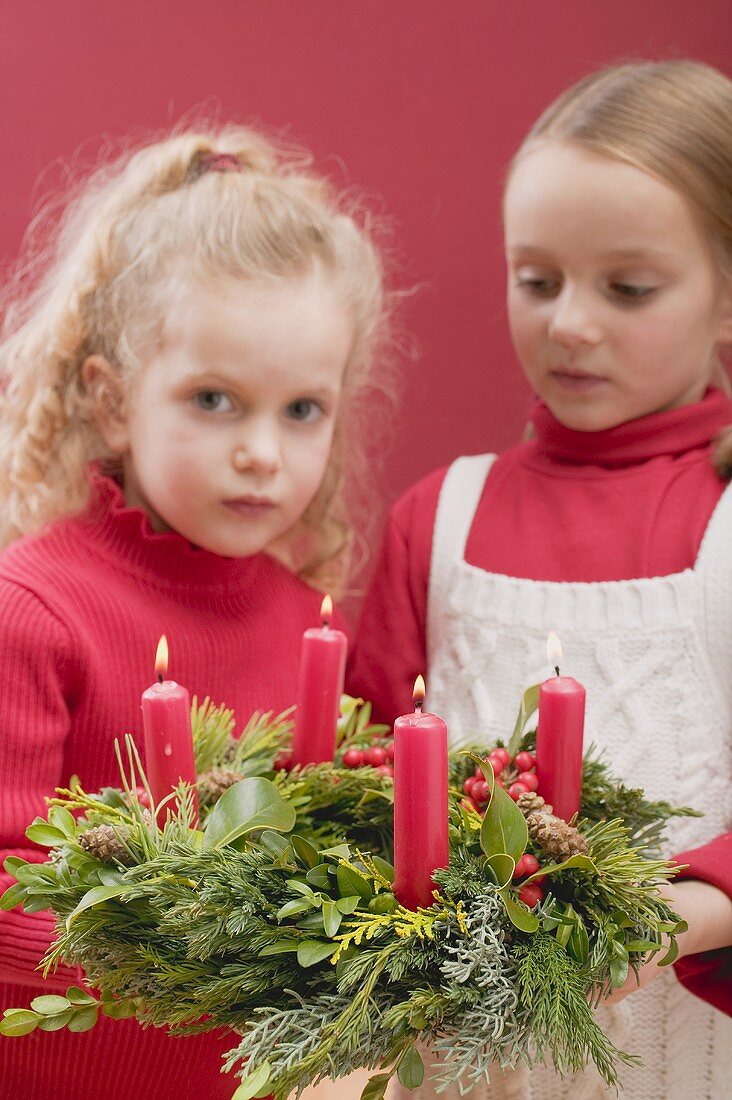 Zwei kleine Mädchen halten Adventskranz