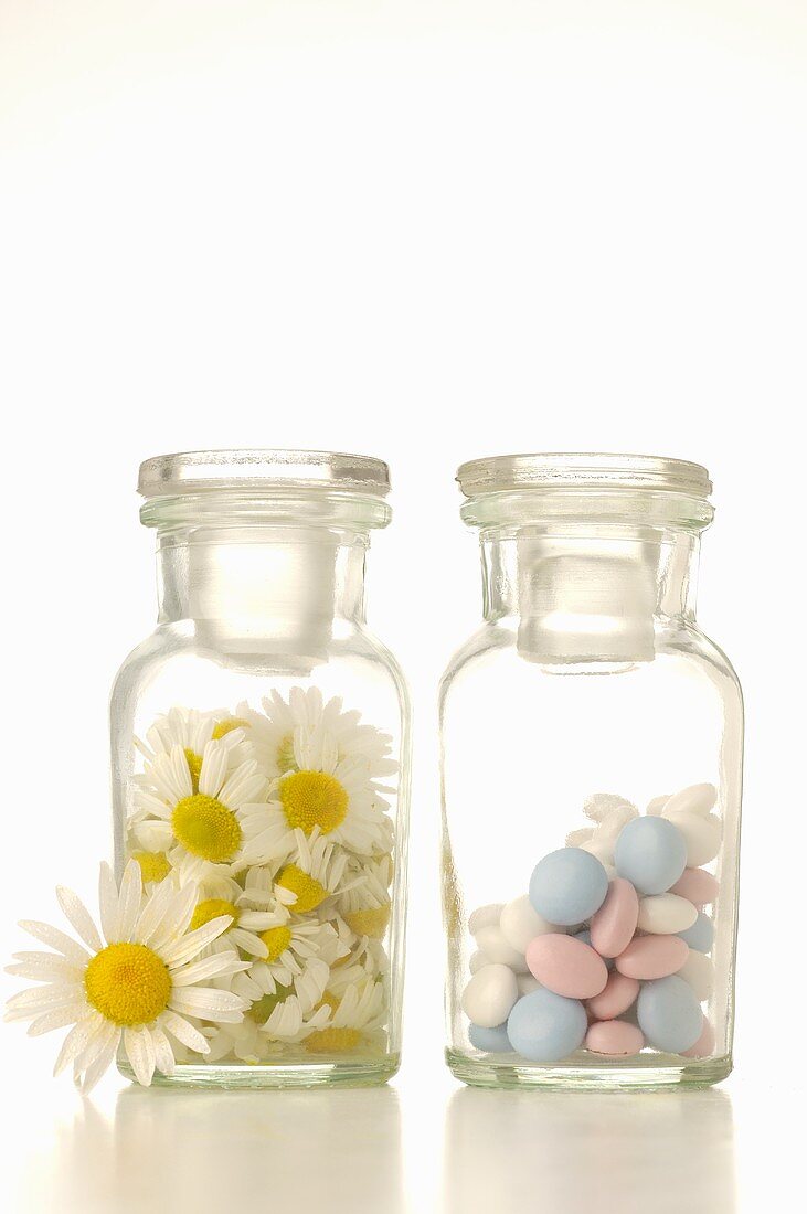 Kamillenblüten und Tabletten in Apothekerflaschen