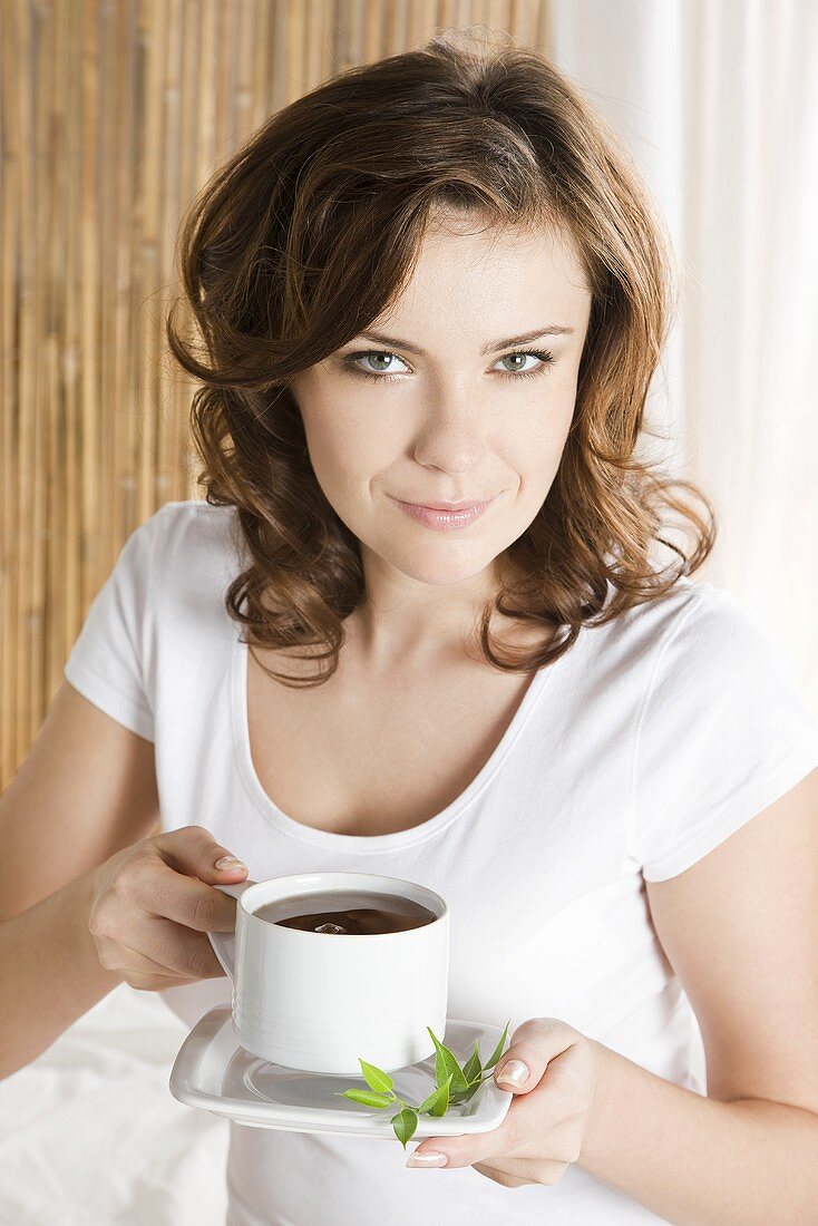 Junge Frau trinkt Kaffee im Bett