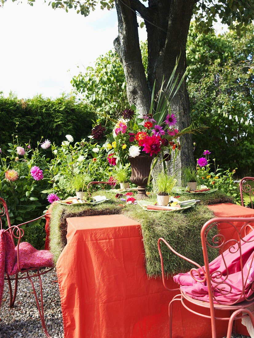 Gedeckter Tisch mit Blumen und Rollrasen dekoriert im Freien
