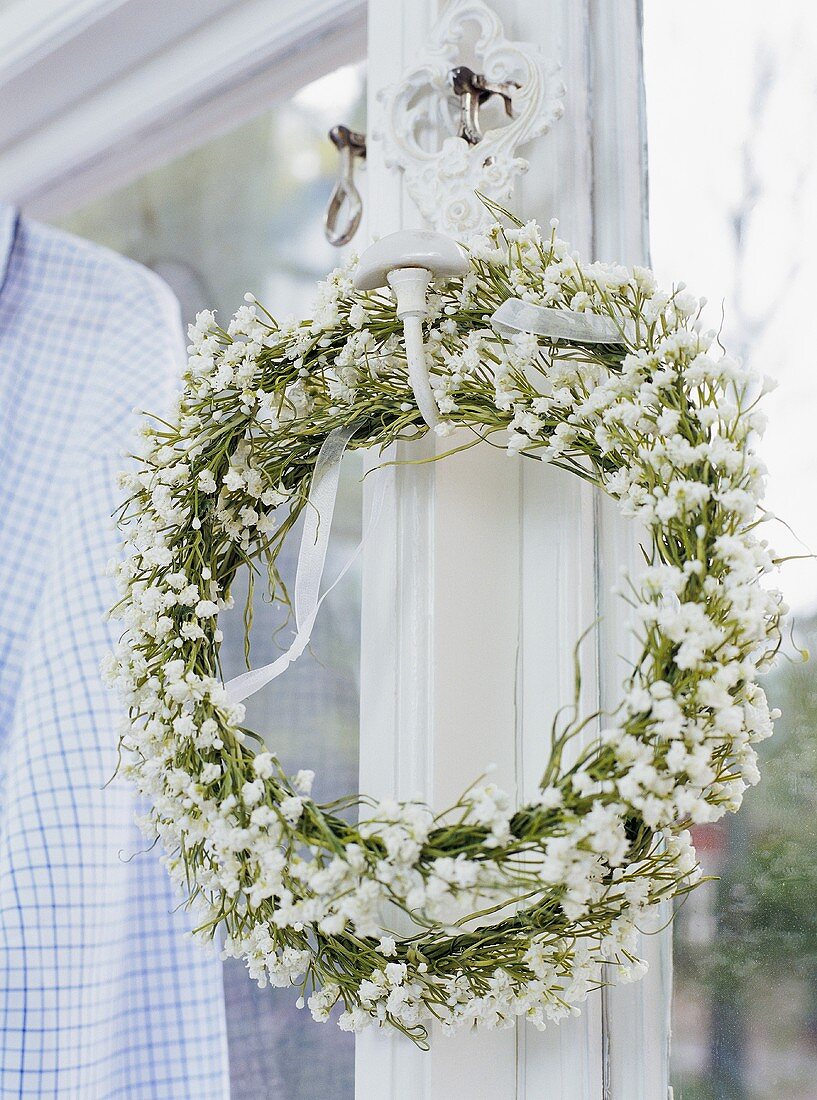 Kranz mit weissen Blüten am Fenster