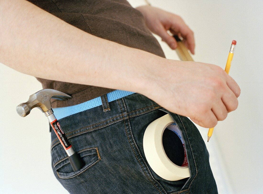 Man with hammer and sticky tape in his trouser pockets