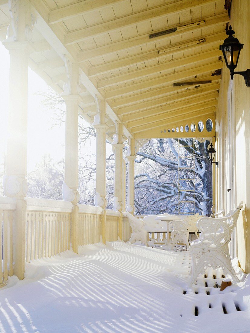 Verschneite Veranda eines schwedischen Landhauses in der Wintersonne