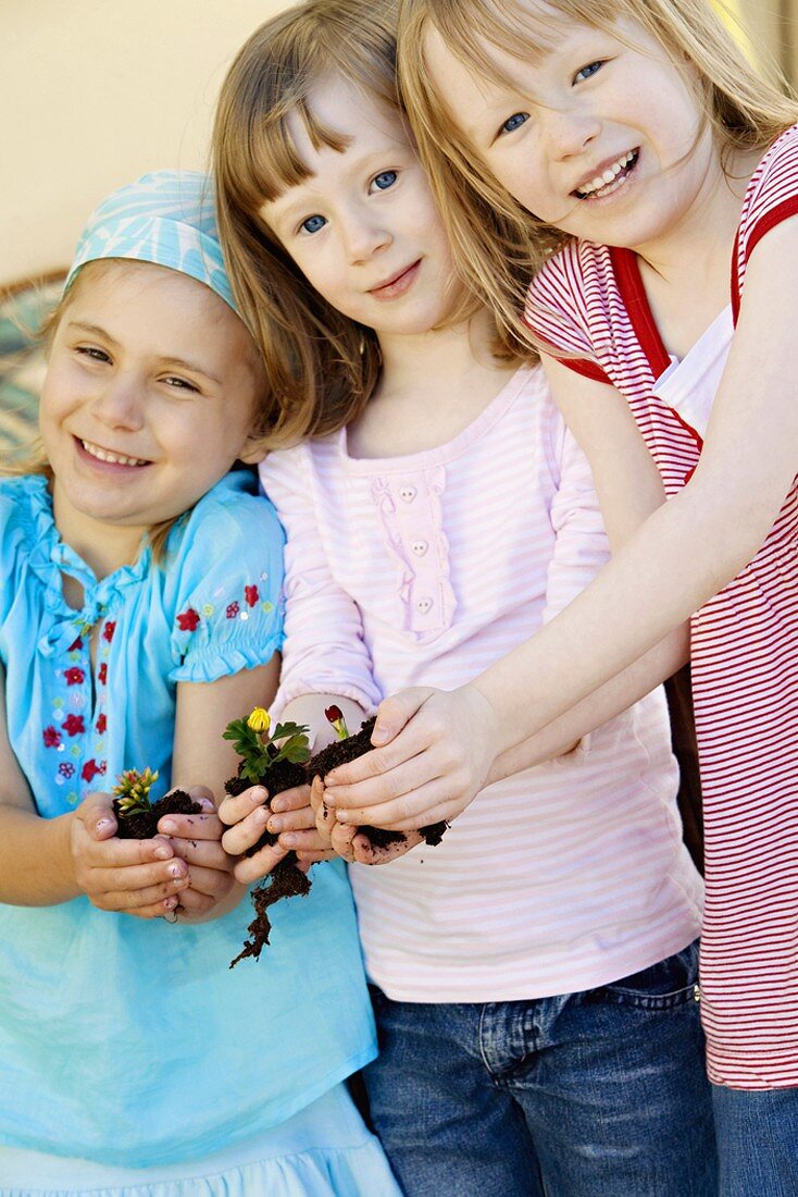 Three girls holding flowerpots