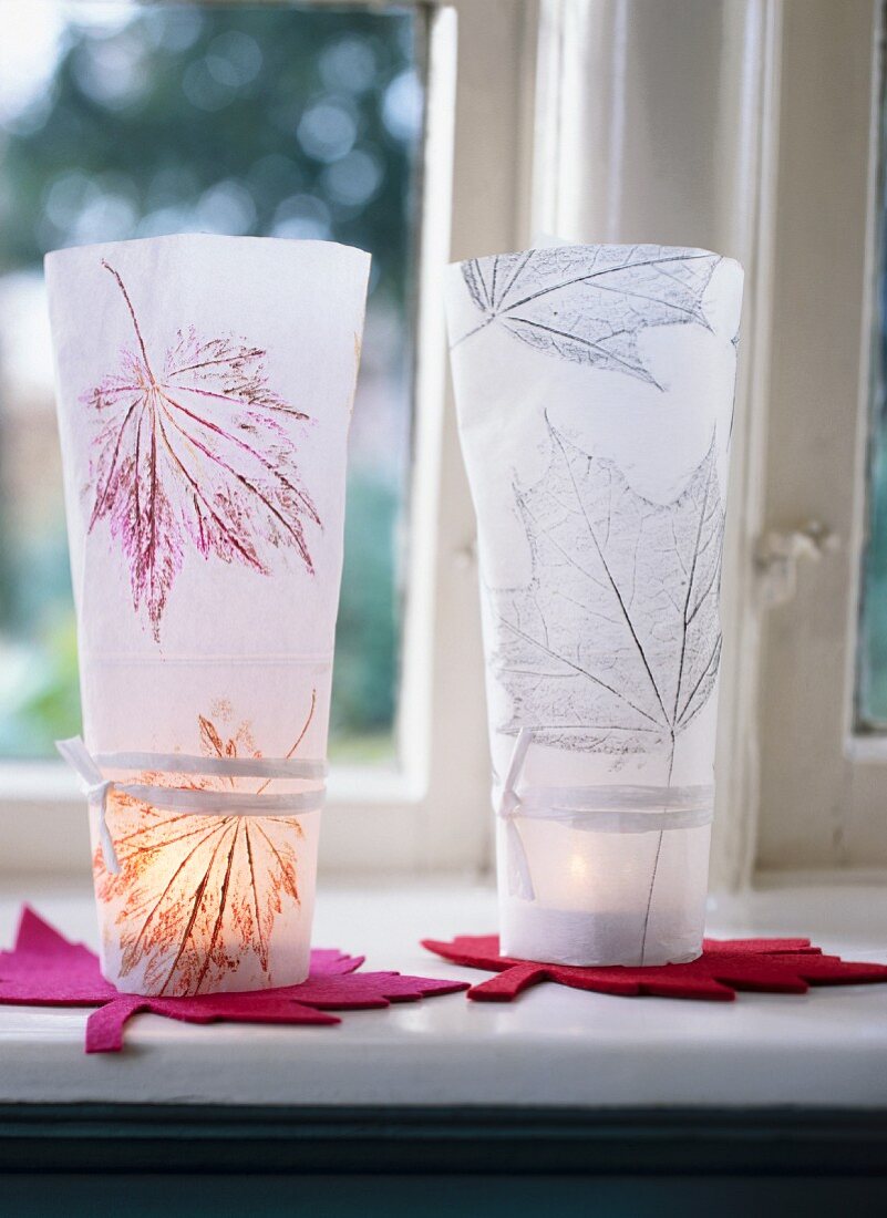 Close-up of two leaf-patterned hand-crafted candle lanterns on windowsill