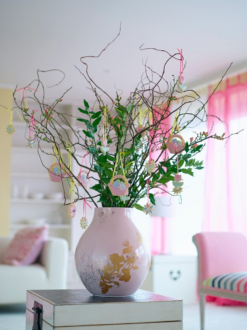 Zweige mit Osterschmuck in rosafarbener Vase