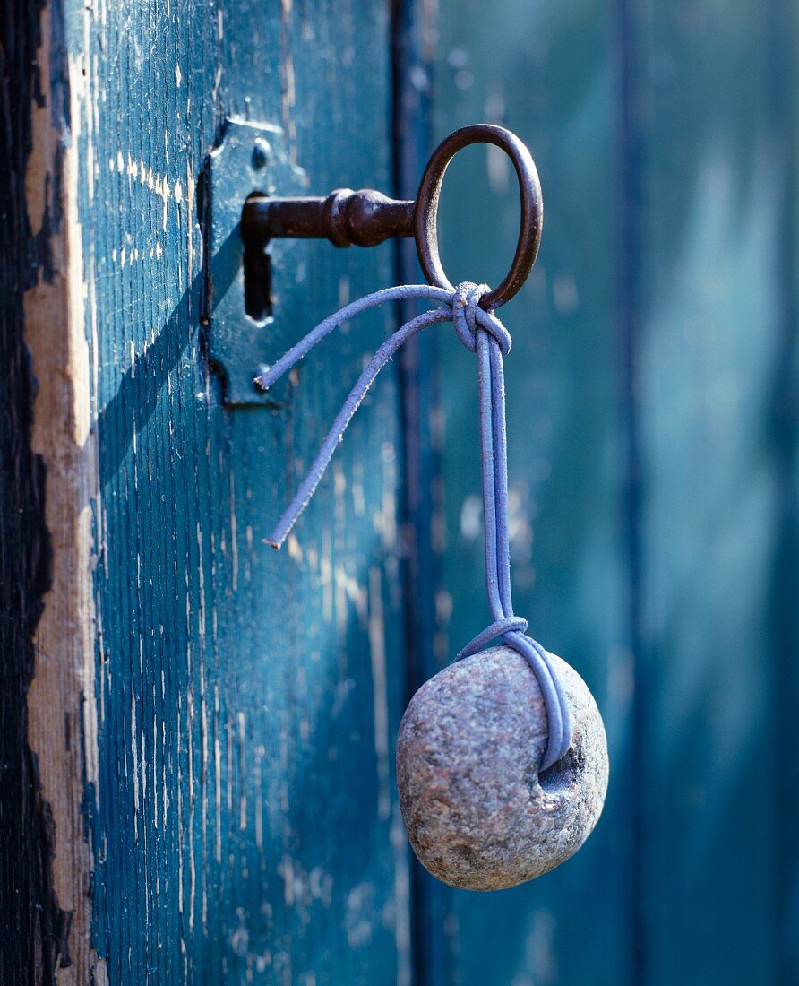 Schlüssel mit Stein als Anhänger im Schloss einer blauen Vintage Tür