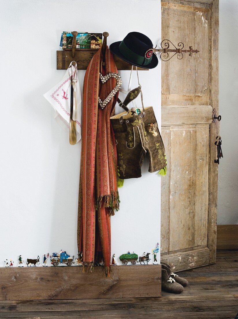 Souvenirs aus den Alpen auf Wandhakenleiste aufgehängt in rustikalem Vorraum