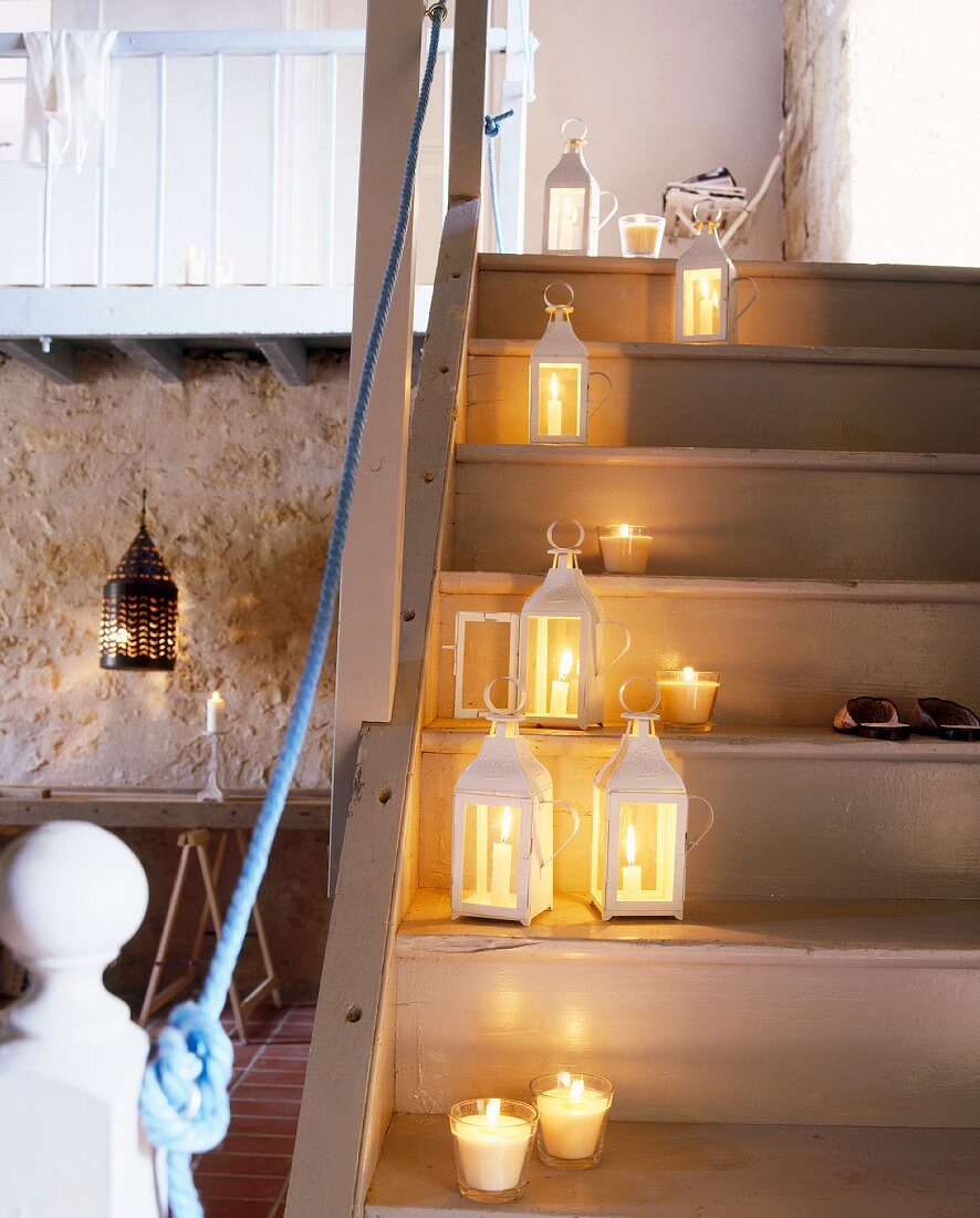 Burning candles and lanterns on a flight of wooden stairs