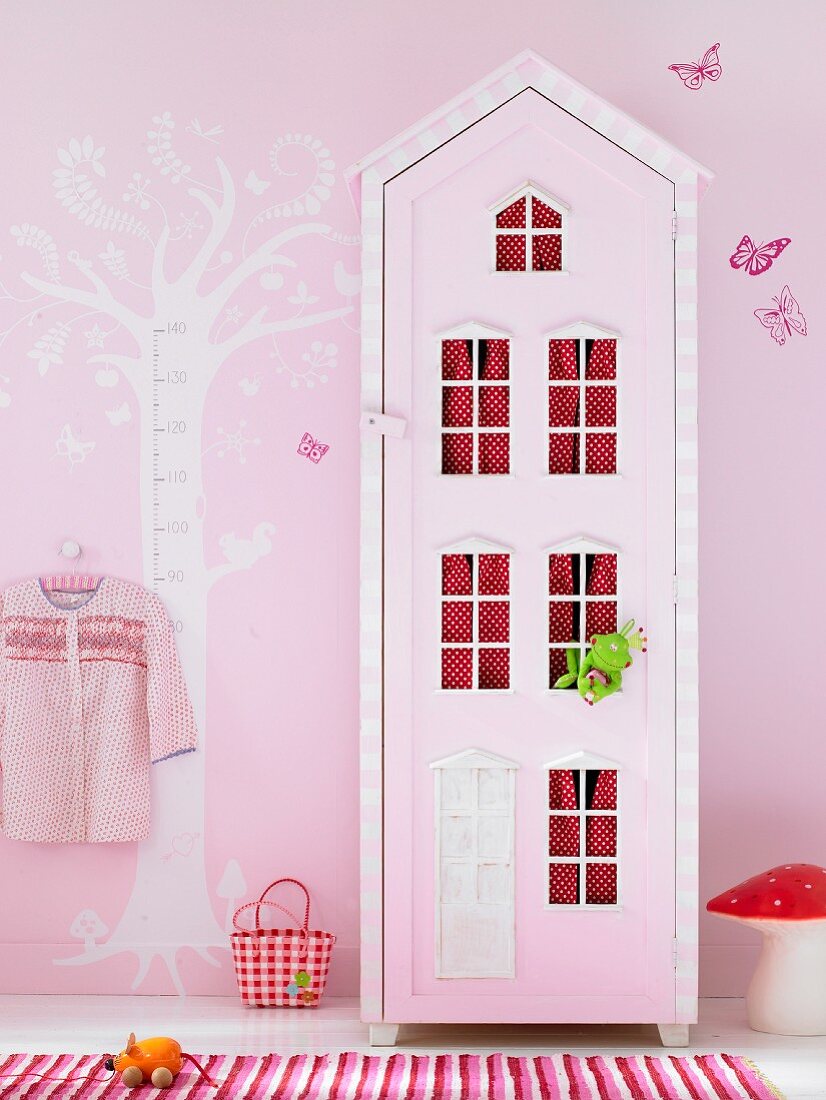 Kinderzimmer in Rosatönen mit Wandschrank in Hausform und aufgemaltem Baum als Messlatte