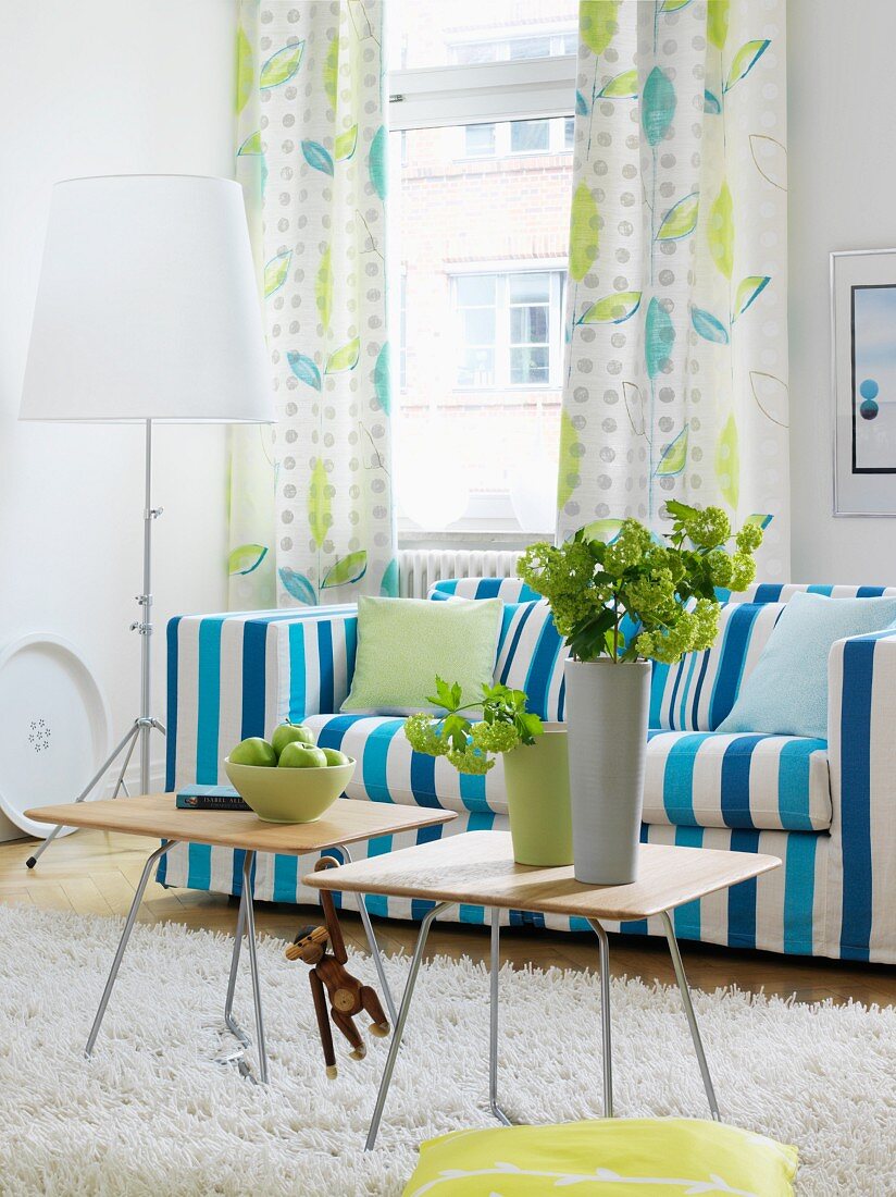 Wohnzimmer mit blau-weiss gestreiftem Sofa und Vorhang mit Blättermotiv