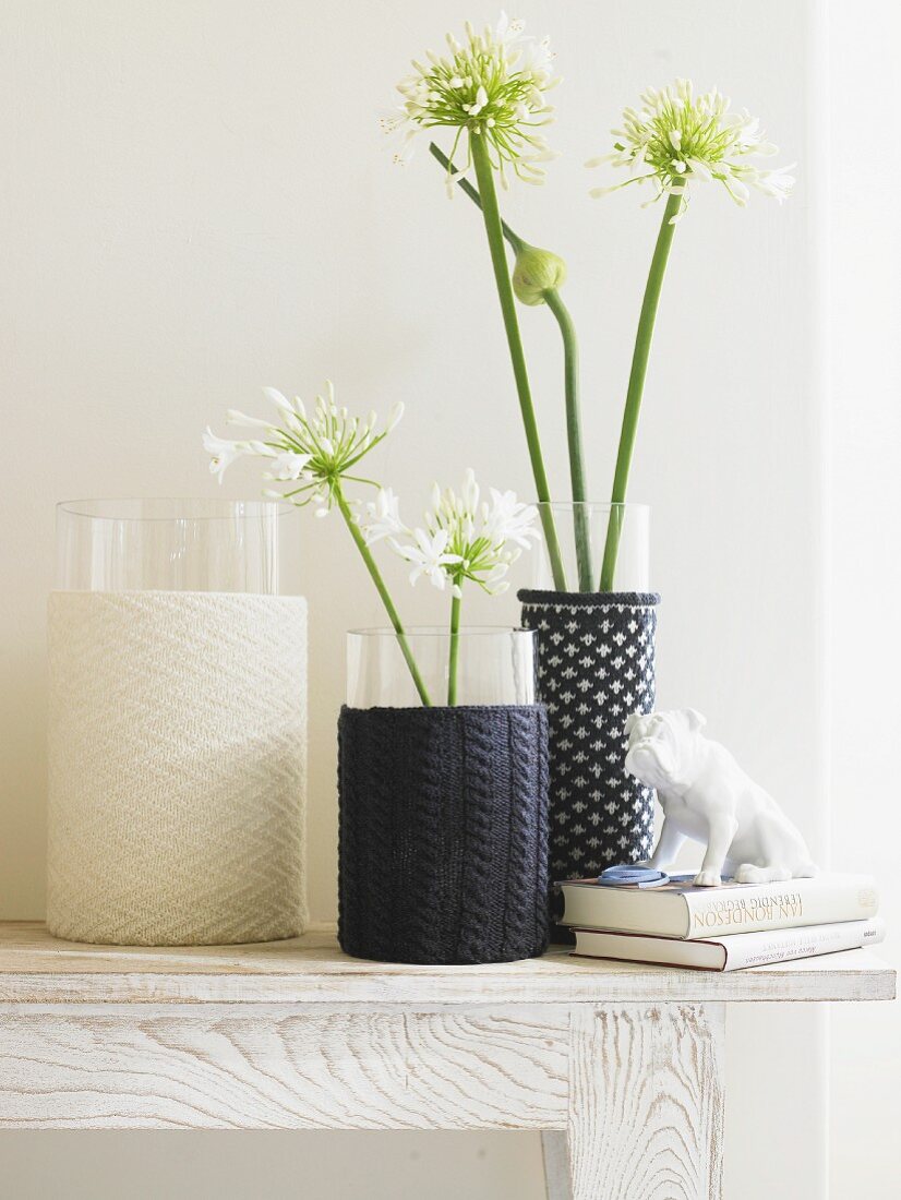 Drei Vasen mit selbstgemachten Strickhussen auf Wandtisch
