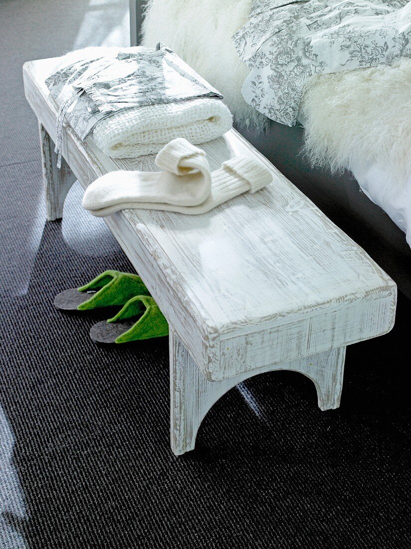 Weissgestrichene Bettbank aus Holz als Ablagemöglichkeit
