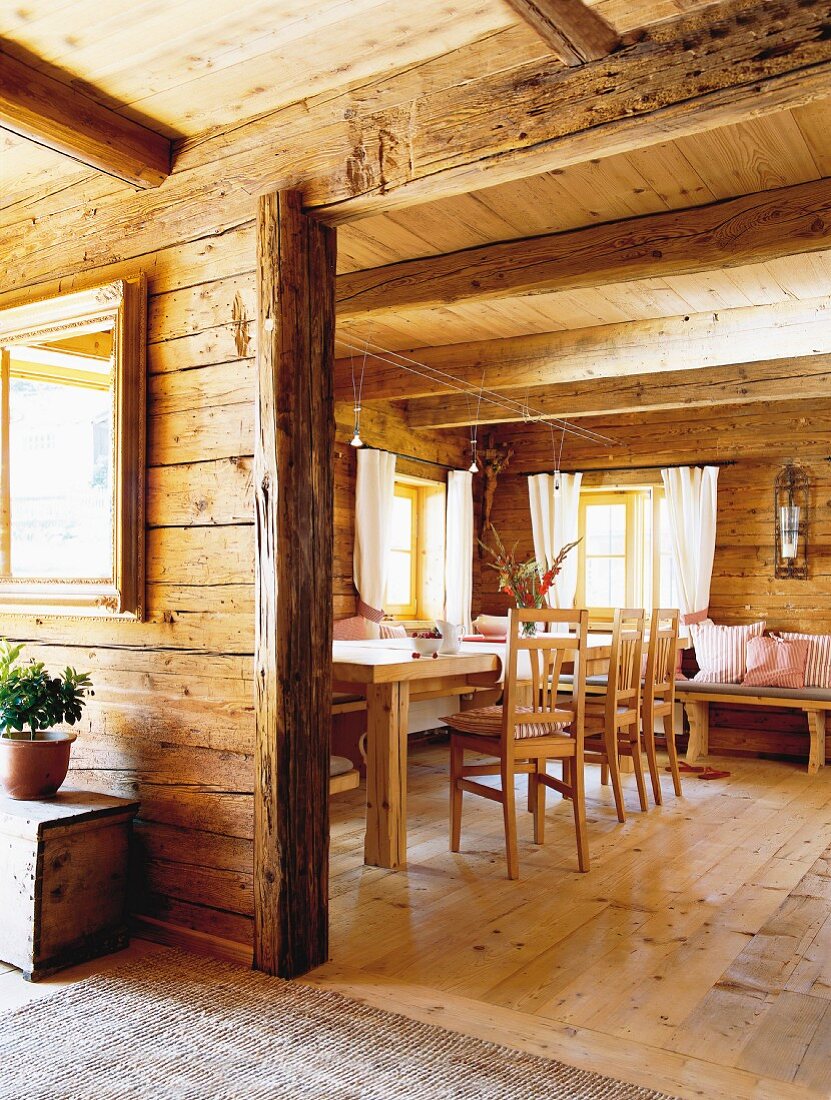 View into rustic interior with dining table and wood-beamed ceiling