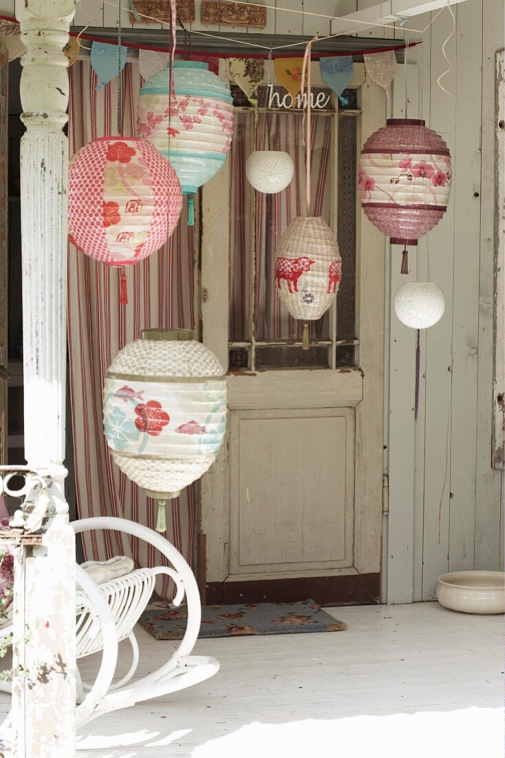 Various painted paper lanterns and a partially visible rocking chair on a terrace