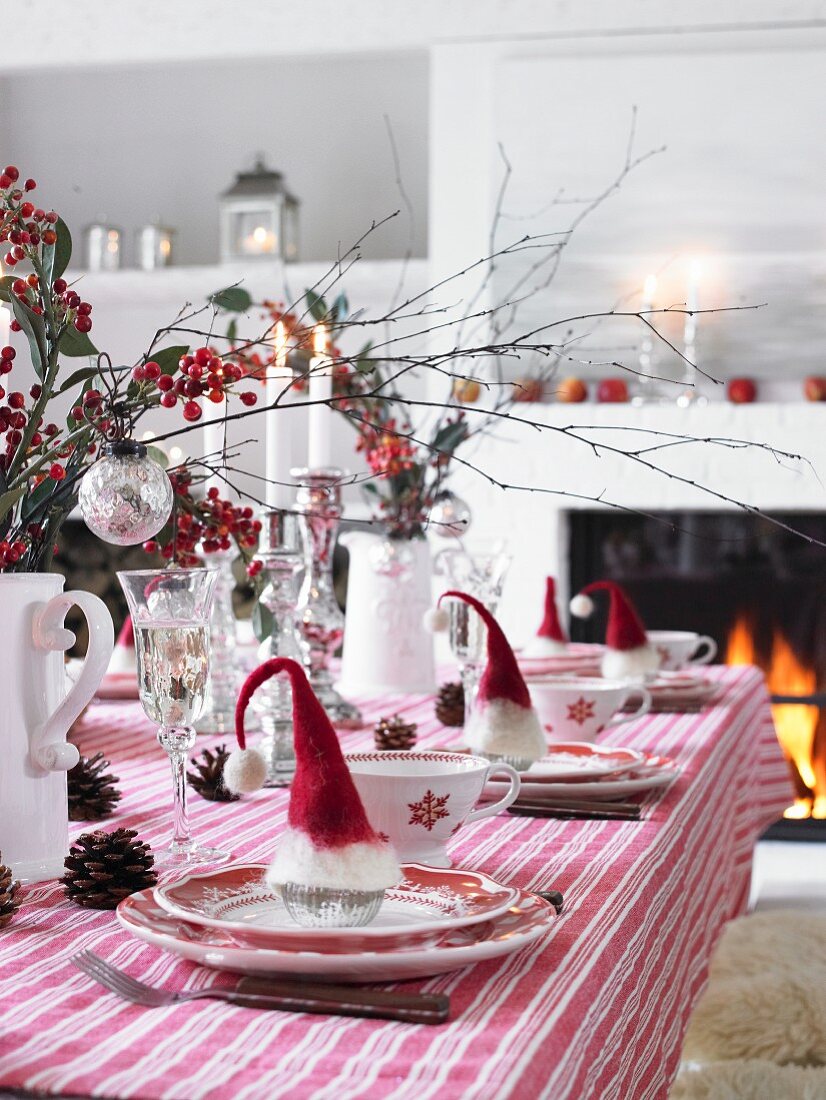 Weihnachtlich gedeckter Esstisch in Rot-Weiß am lodernden Kaminfeuer