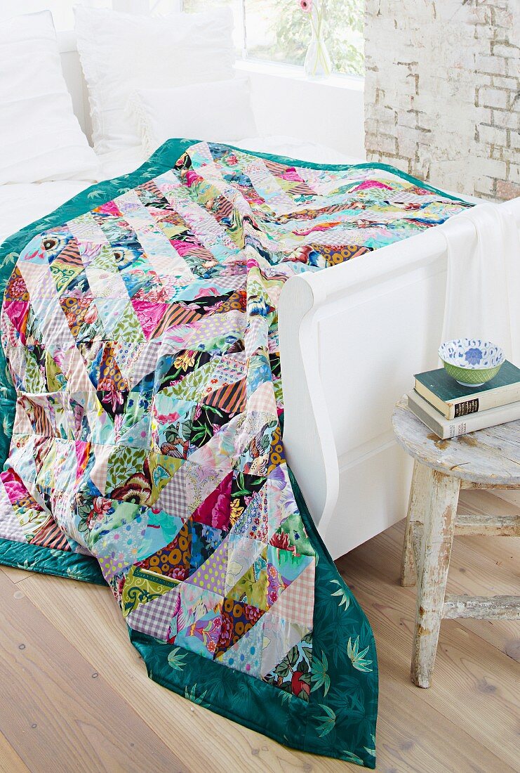 Patchwork blanket on white, wooden bed