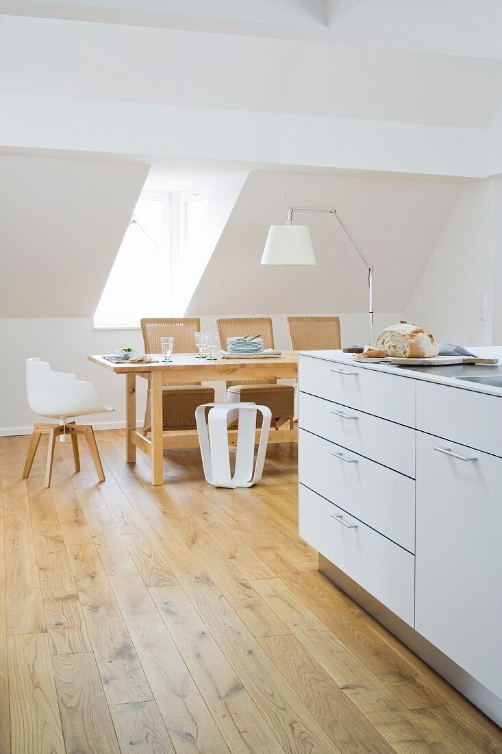 The attic room of an old town house with a kitchen counter and a dining table