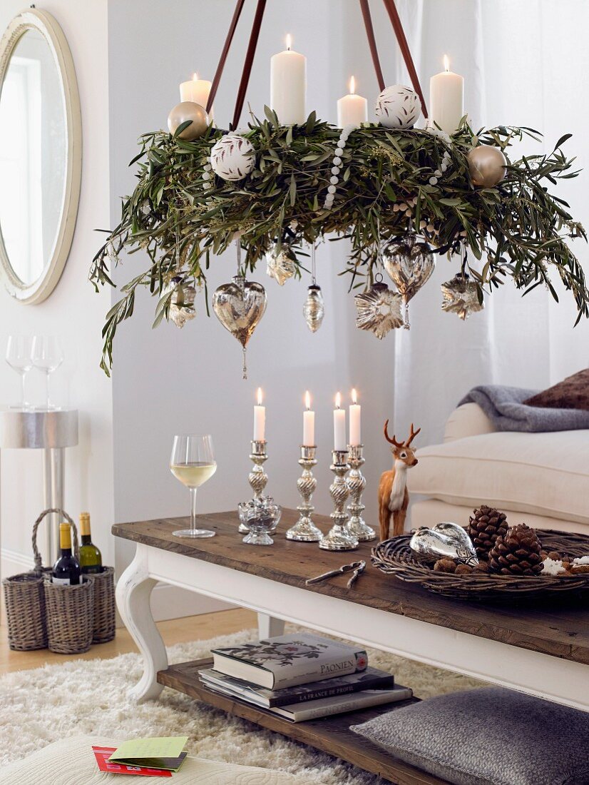 A hanging advent wreath made from olive twigs with silver balls and white candles