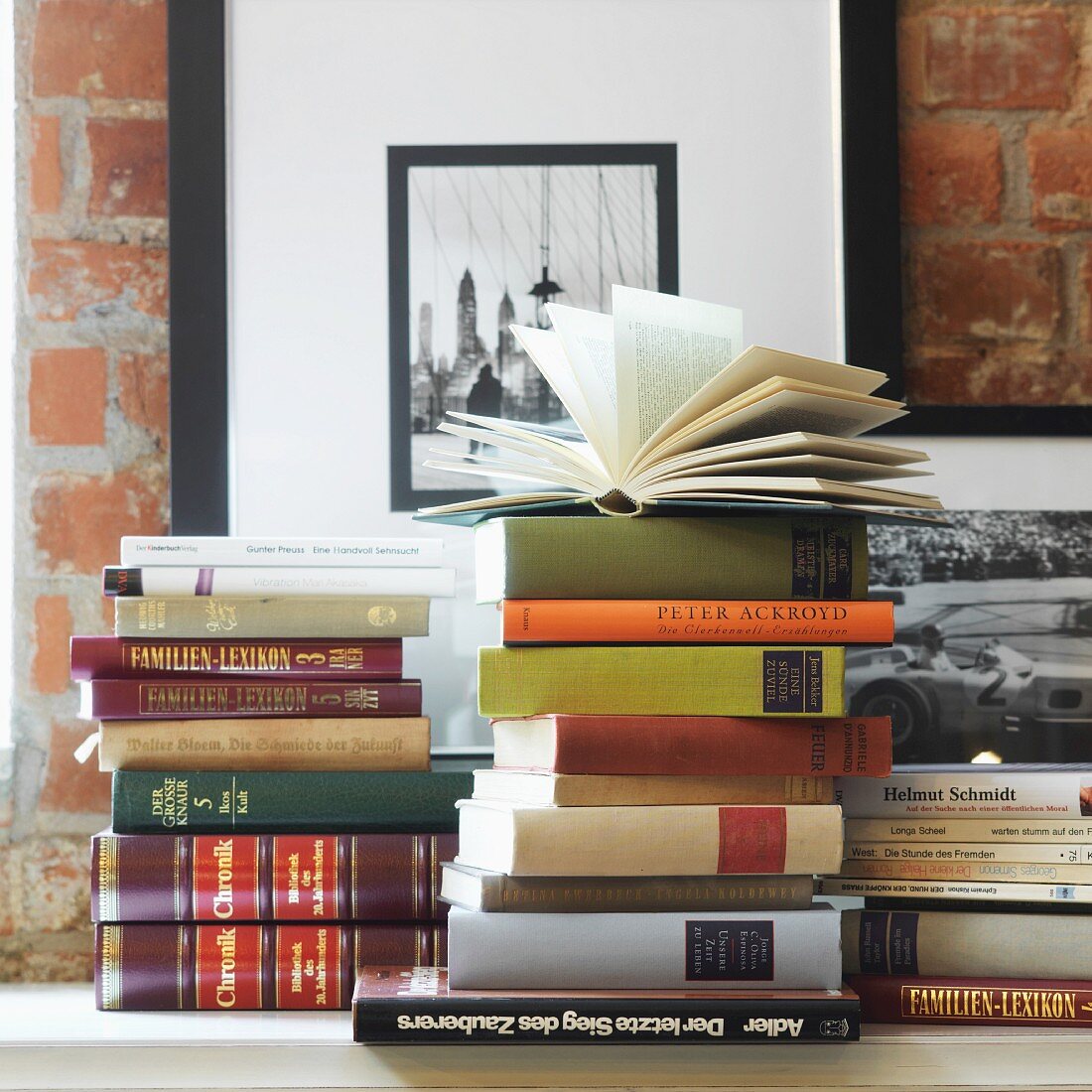 Books stacked on surface against brick wall