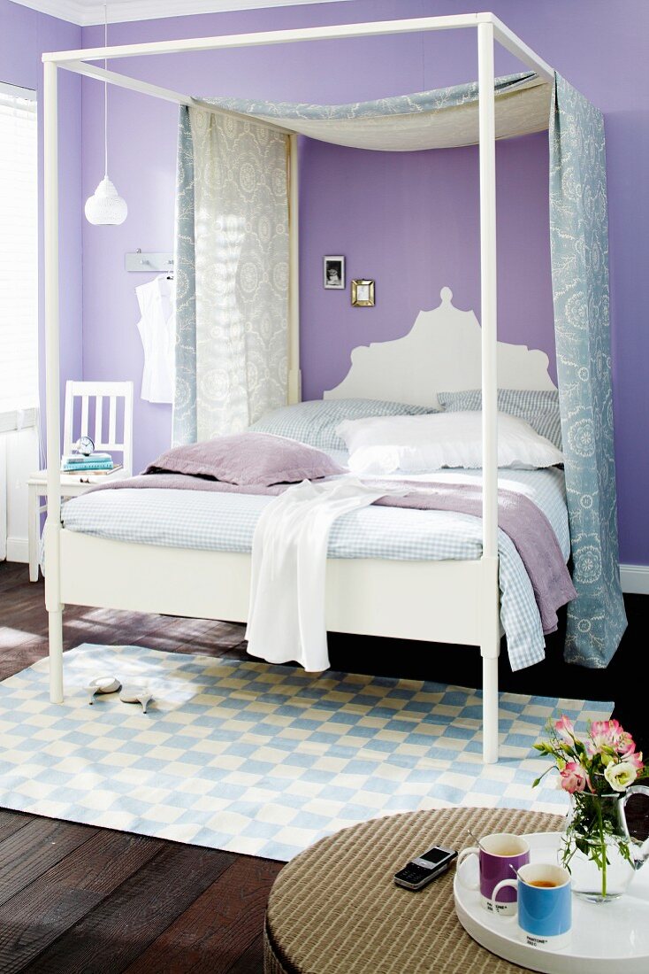 Canopied bed in bedroom with lilac walls