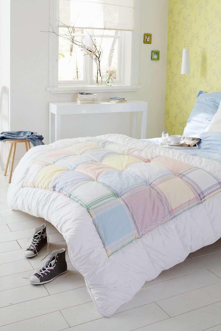 Bed with patchwork quilt in simple bedroom