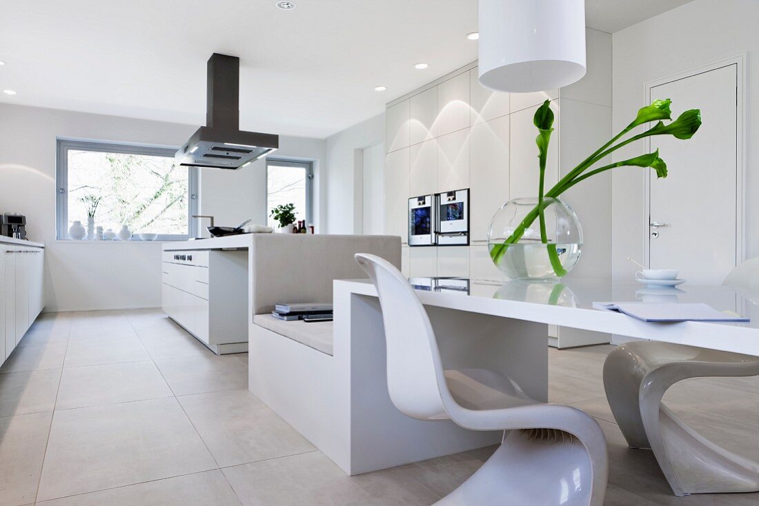 A spacious, modern kitchen in white with a long eating and seating area