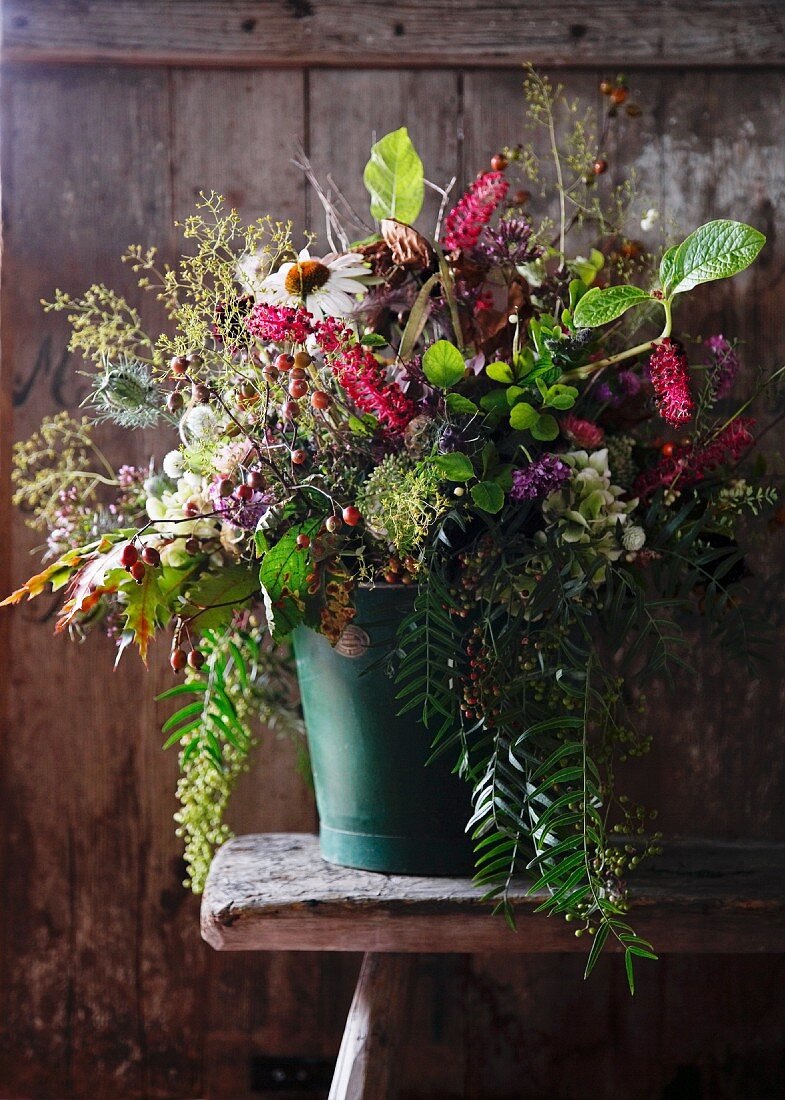 Herbstlicher Blumenstrauss in Vase auf Holzhocker