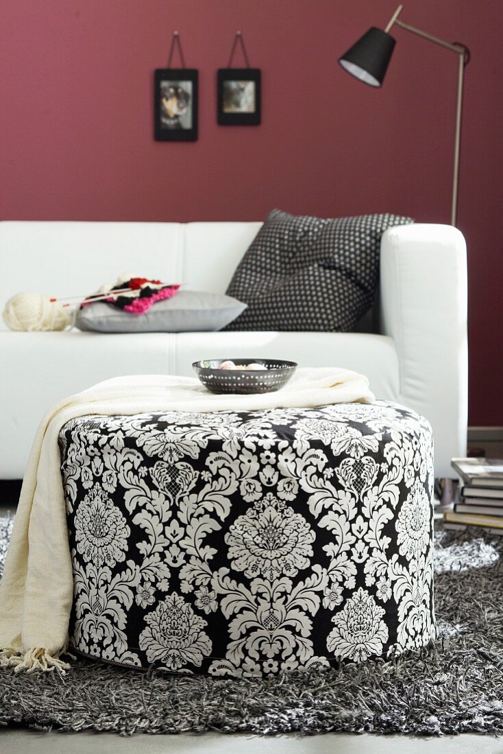 Living room with sofa & black and white patterned pouffe used as side table