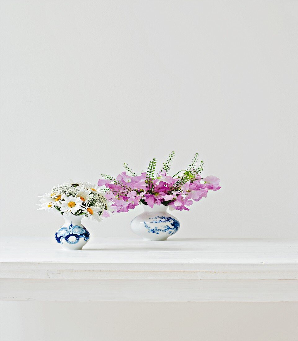 Zwei kleine Blumensträuße - Margeriten und Wicken - auf weißem Tisch