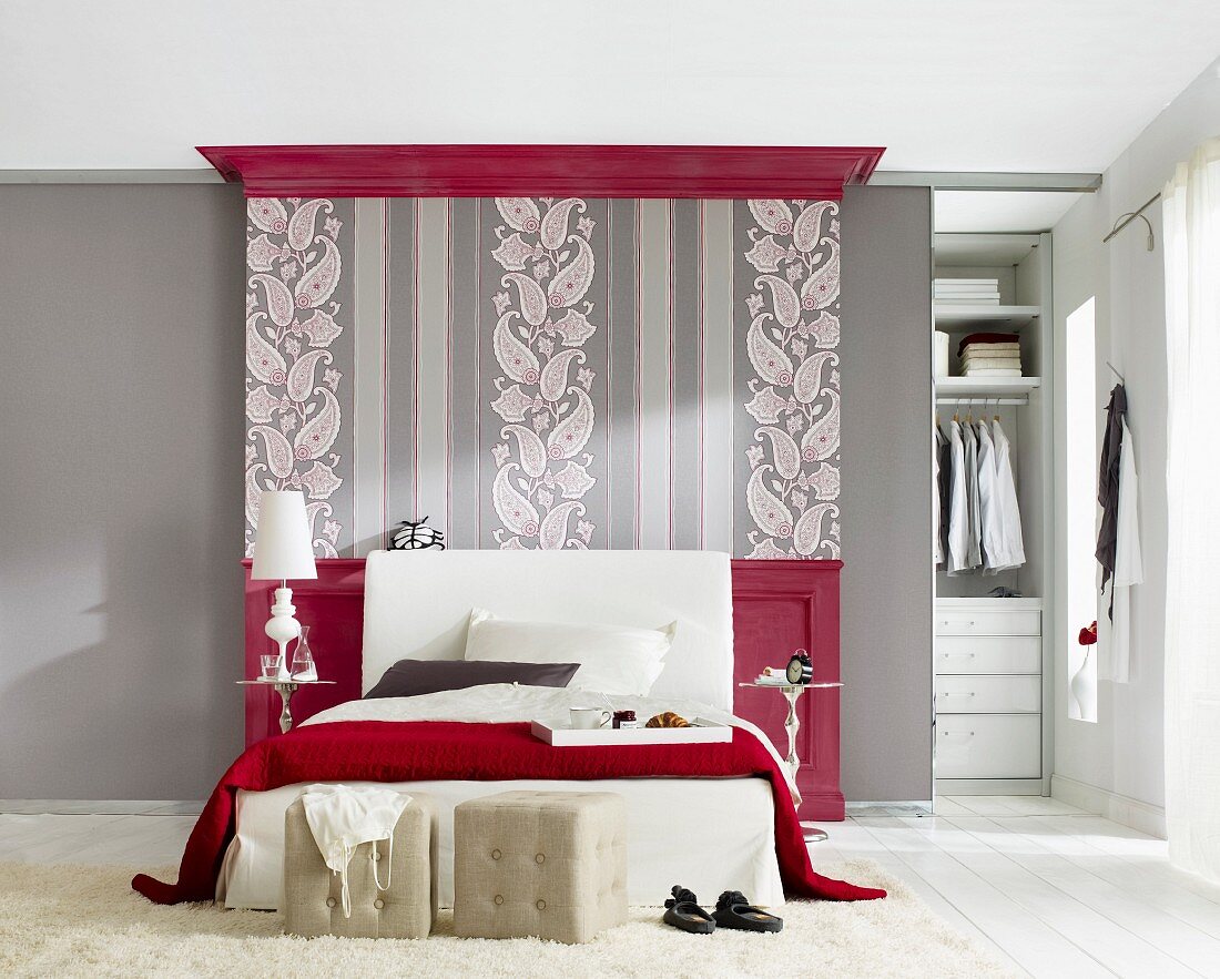 Bedroom in grey and red, wallpaper with pattern of paisley and stripes behind bed