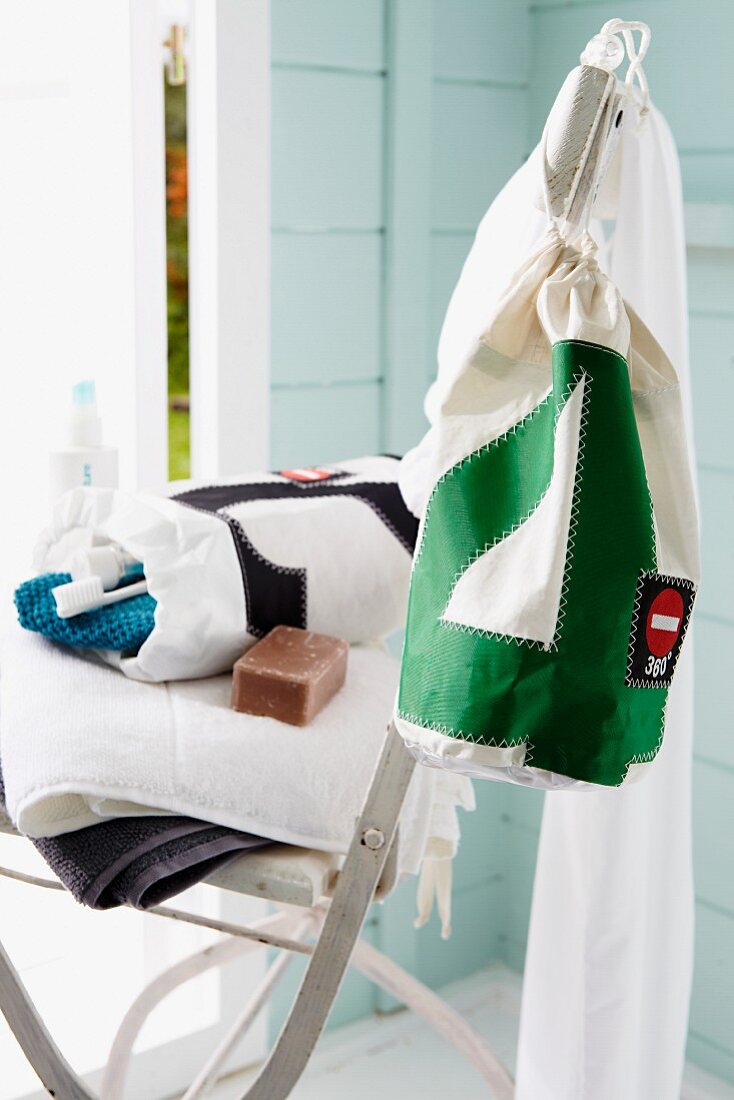 Towels & bag of toiletries on folding chair in Scandinavian guest house