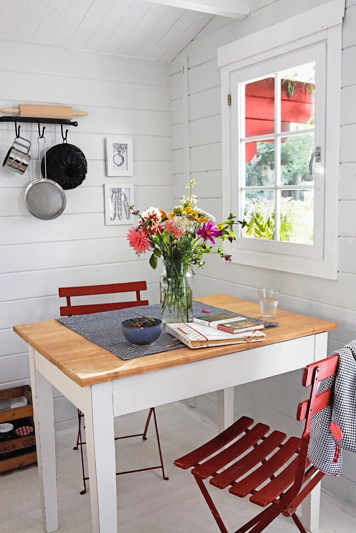 Esstisch mit roten Klappstühlen in skandinavischem Gartenhaus