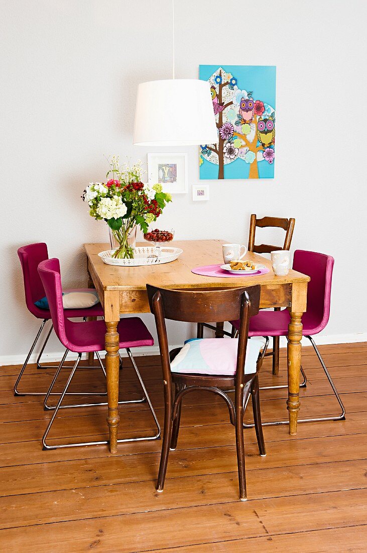 An antique wooden table being used as a dining table with various different chairs