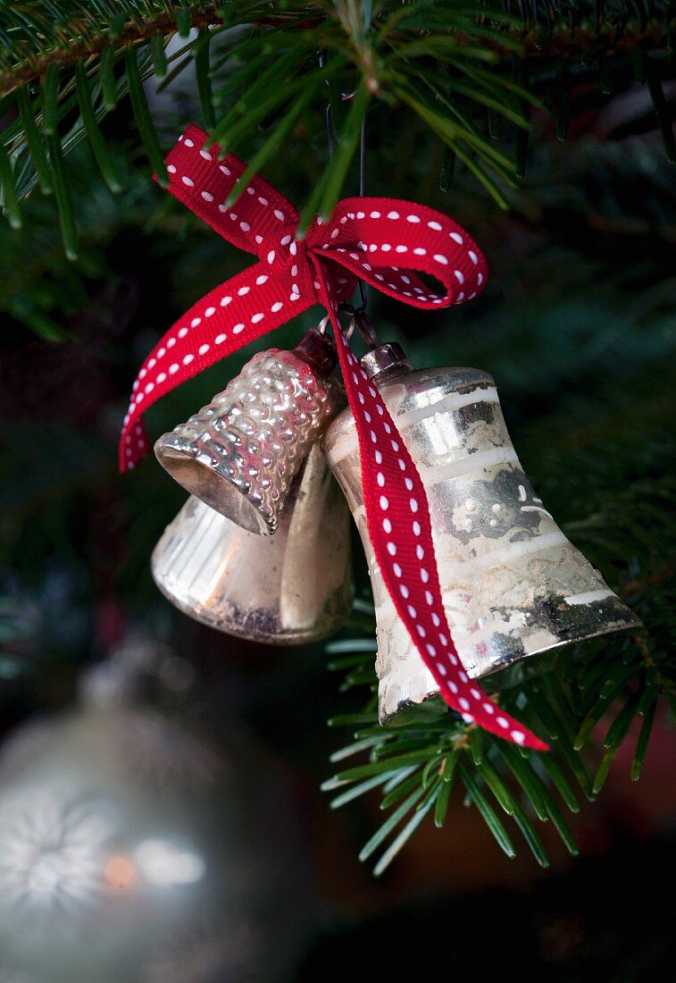 Silver bells with a red bow on a Christmas tree