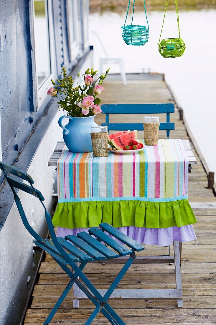 A small table with a linen table runner and chairs on a jetty