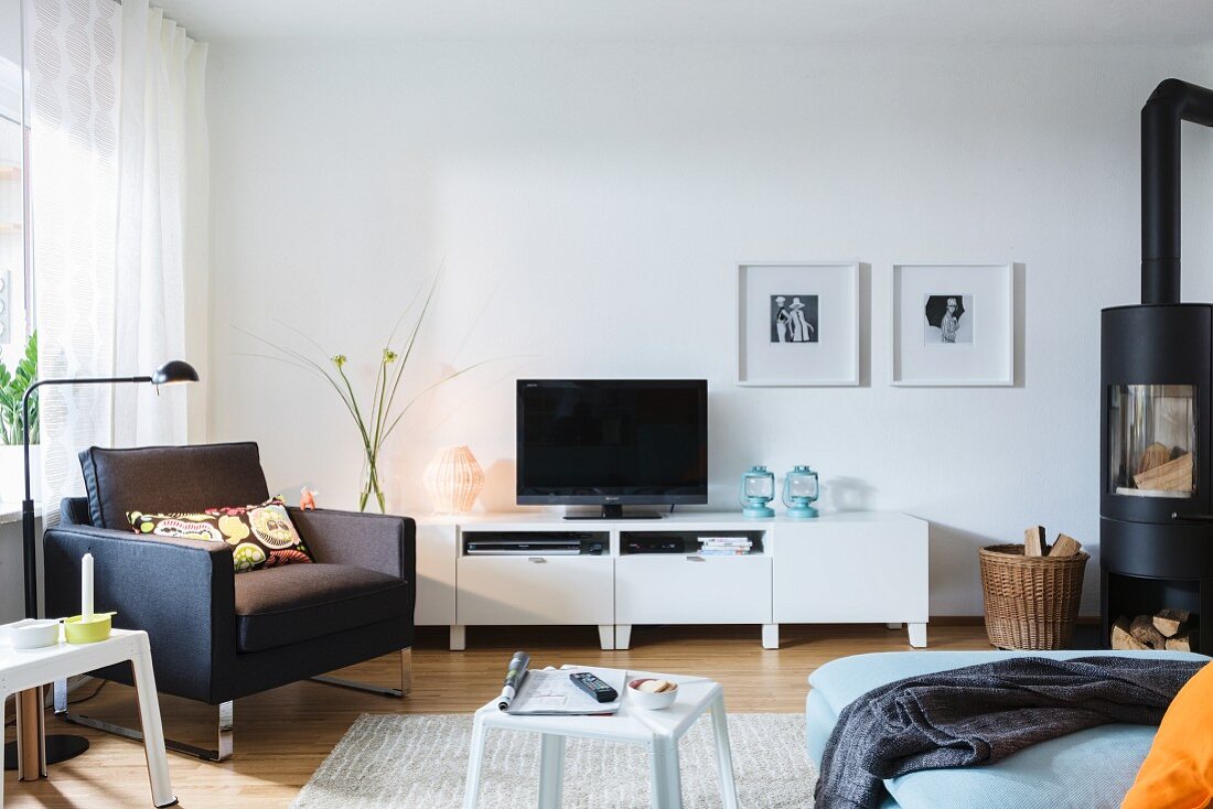 Schwarzer Sessel vor Fernsehregal, und Schwedenofen im Wohnzimmer
