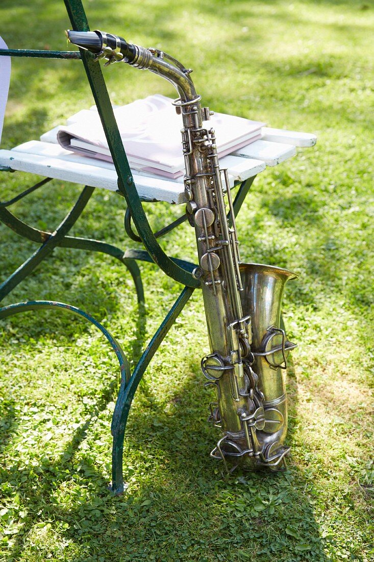 An Gartenstuhl angelehntes Saxophon auf Rasen