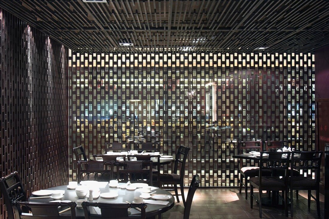 Speisezimmer mit gedeckten Tischen vor Holzgitter Paneelen an Wand und Decke