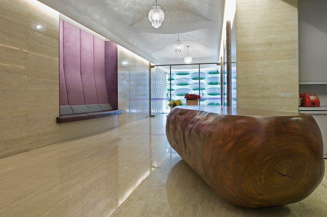 Monolithische Theke aus Holz im minimalistischen Vorraum mit poliertem Steinboden