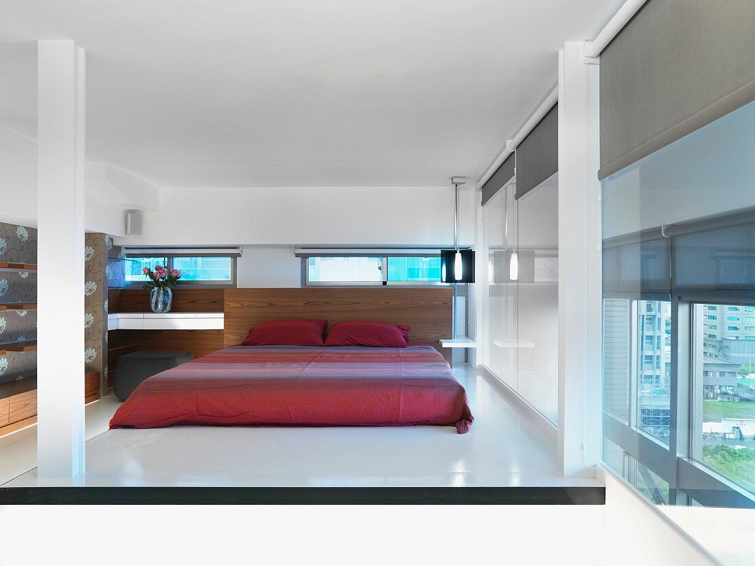 Doppelbett mit roter glänzender Tagesdecke in elegantem Schlafzimmer