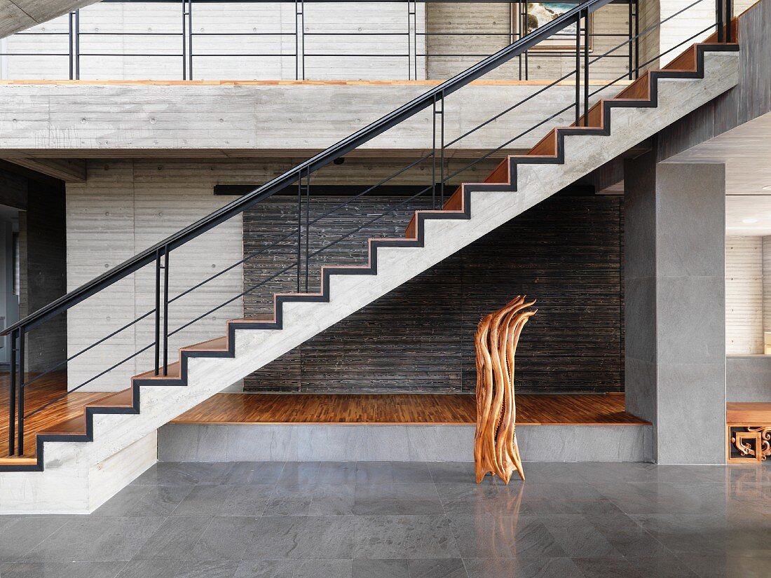 Treppenaufgang aus Beton mit Holzbelag in minimalistischer Eingangshalle