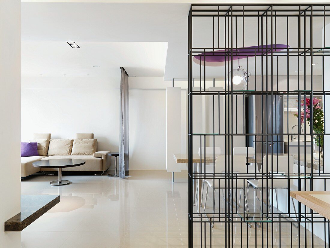Offener Wohnraum mit transparentem Regal aus schwarzem Metallgitter als Raumteiler