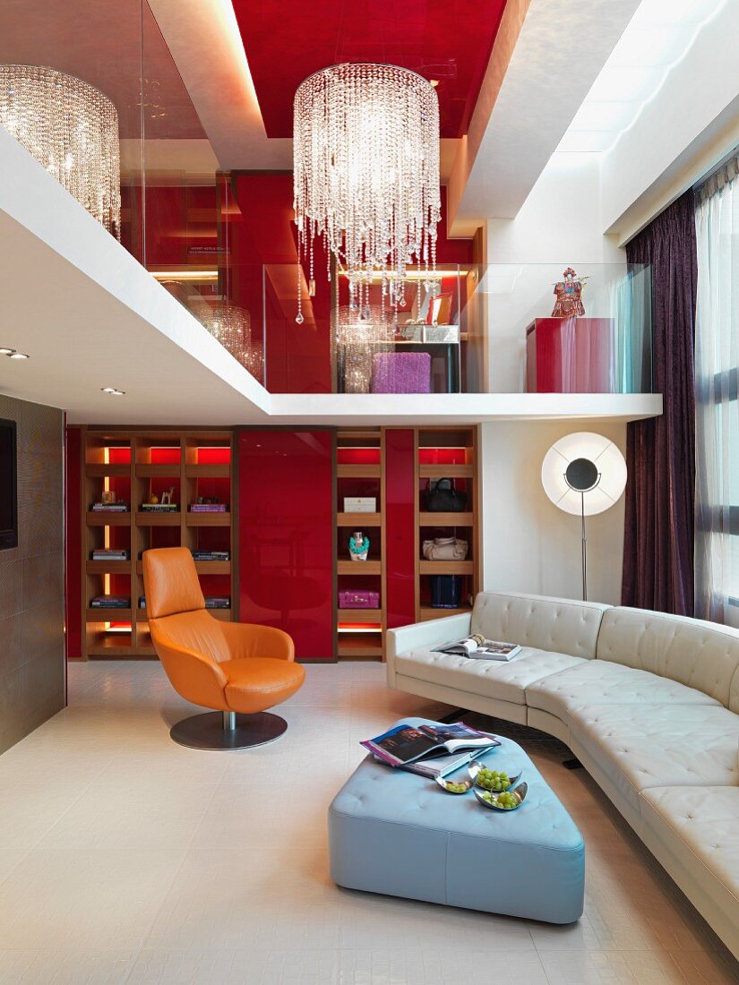Nach oben offener Wohnraum mit Polstercouch und Blick auf Galerie und Kronleuchter an roter Decke