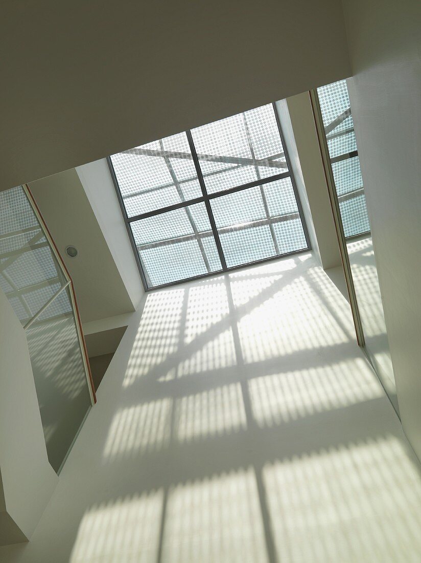 Treppenhaus mit Glasdecke und Lichtschattenspiel an Wand