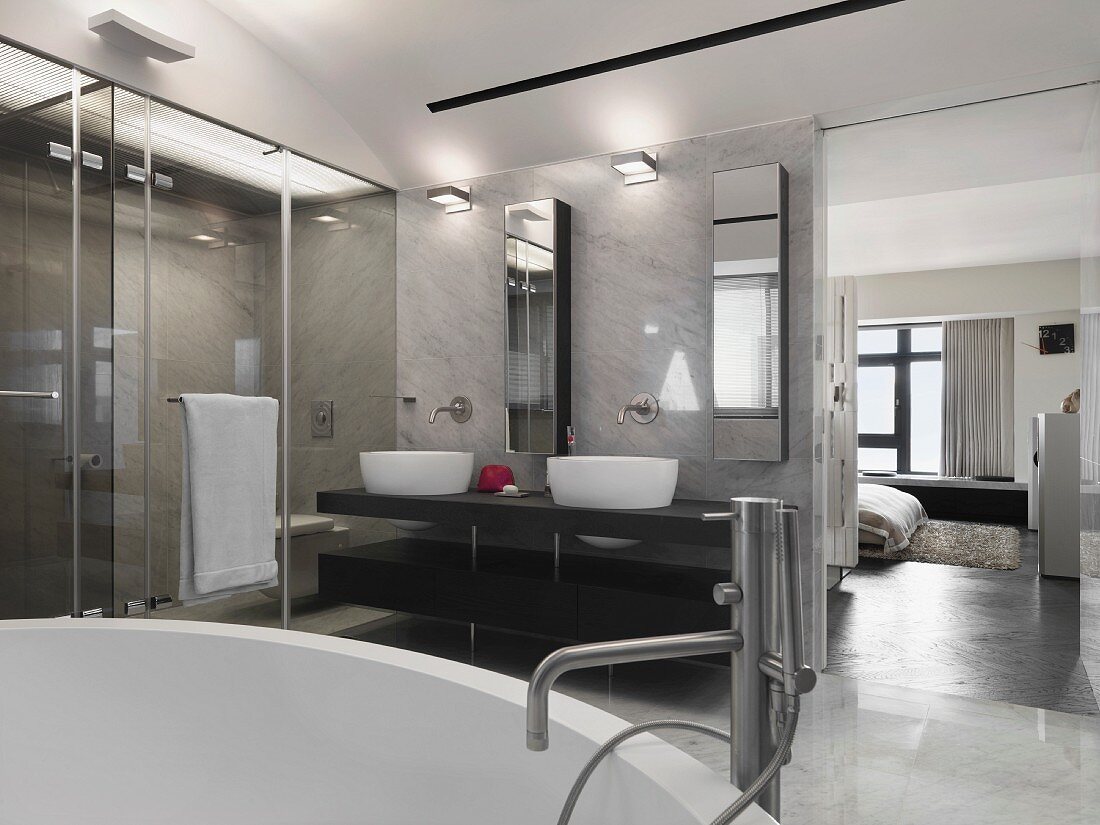 Designer Bad mit elegantem Waschtisch vor Marmorwand neben raumhohem Durchgang in Schlafraum