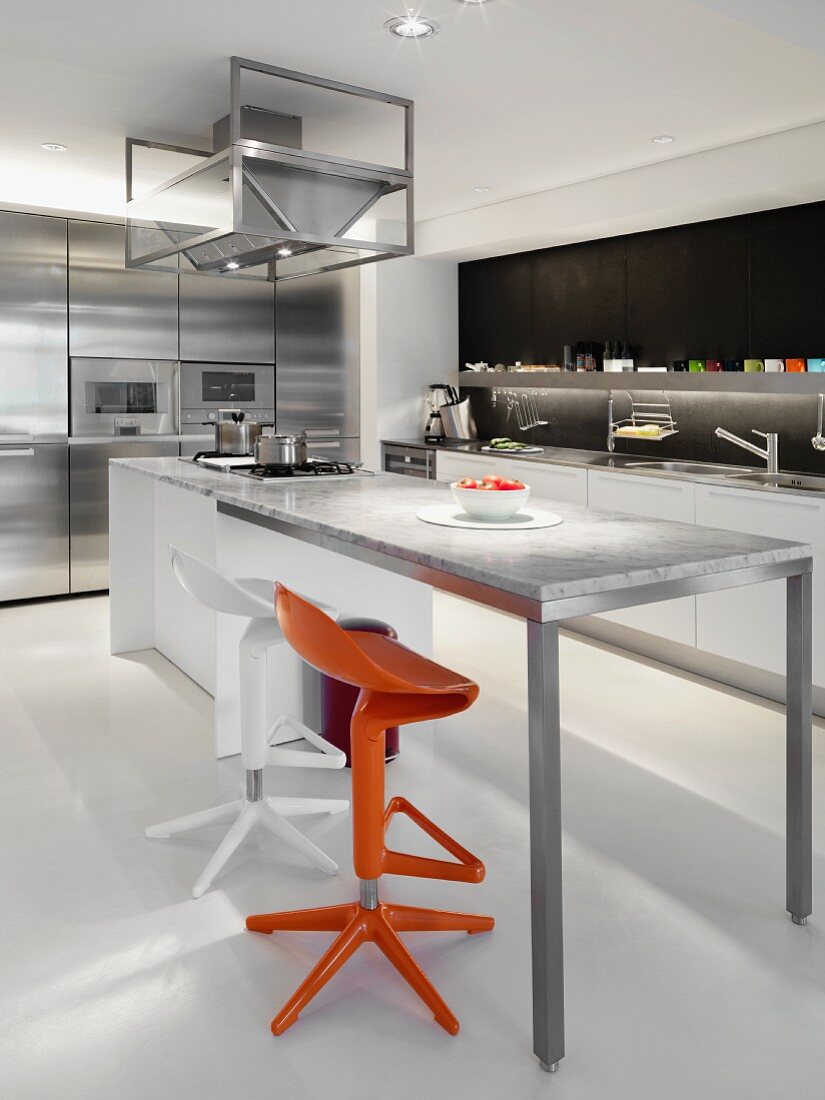 Designerküche mit farbigen Bistrohockern vor hohem Tisch und Marmorplatte