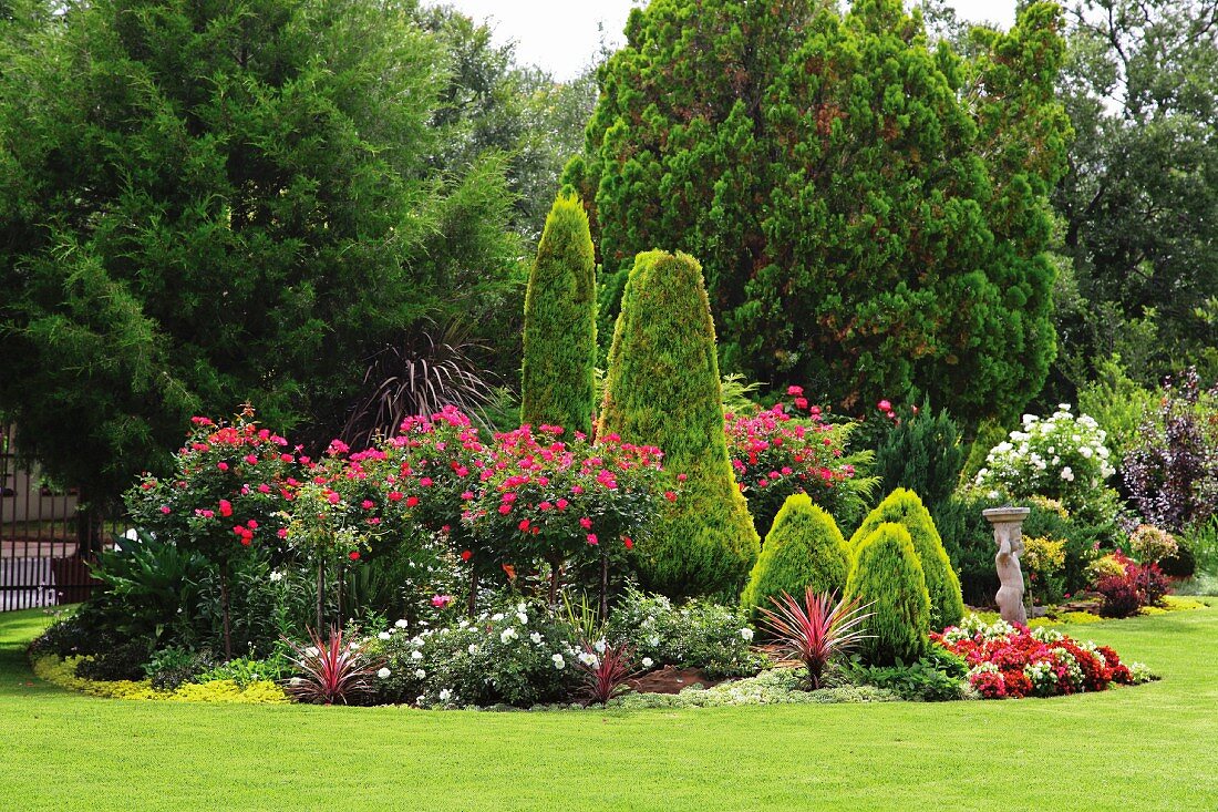 Elegante Gartenanlage mit Steinfigur und üppig blühenden Gartenpflanzen